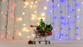 Shopping trolley with christmas balls and tree with garlands.