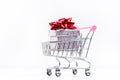 Shopping trolley with christmas gift. Gift box with red ribbon isolated on a white background. Christmas decoration. Royalty Free Stock Photo