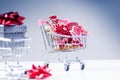 Shopping trolley with christmas gift. Gift box with red ribbon on a white background. Christmas decoration. Royalty Free Stock Photo