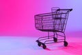 Shopping trolley with copy space over neon purple background