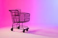 Shopping trolley with copy space over neon purple background