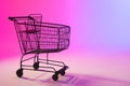 Shopping trolley with copy space over neon purple background