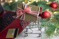 Shopping trolley with gift, keyboard of laptop, credit card, branches of a Christmas tree, balls on a white background