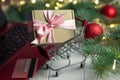 Shopping trolley with gift, keyboard of laptop, credit card, branches of a Christmas tree, balls on a white background