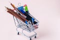 Shopping trolley with stationery items - colored pencils, markers, stapler, clips.