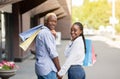 Shopping and walking in city. Smiling african american guy and girl turn around and look at camera Royalty Free Stock Photo