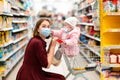 Shopping. A young woman in a medical mask and her baby sitting in a grocery cart, wearing a medical mask. The concept of a new Royalty Free Stock Photo