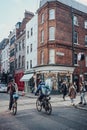 Shops and cafes in Soho, London, UK, people, cyclist and Deliveroo biker in front, motion blur