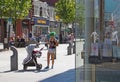 Shops on chapel street merseyside with people walking in the pedestrian ara and a young mother with green hair with a baby in a