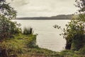 Shore of the forest lake during a strong, prolonged rain in cloudy weather. On the water bubbles from drops Royalty Free Stock Photo