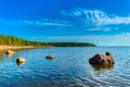 The shore of the gulf of finland of the baltic sea on a sunny summer day. Green pines, blue sky, huge boulders in the water and on Royalty Free Stock Photo