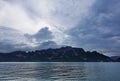 On the shore of the lake, against the background of a cloudy sky, whimsical rocks rise.