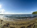 Shore of the lake, sand, lapping waves, blue sky with light clouds, fisheye lens, lake Uvildy