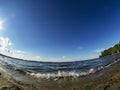 Shore of the lake, sand, lapping waves, blue sky with light clouds, fisheye lens, lake Uvildy