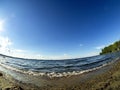 Shore of the lake, sand, lapping waves, blue sky with light clouds, fisheye lens, lake Uvildy