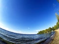 Shore of the lake, sand, lapping waves, blue sky with light clouds, fisheye lens, lake Uvildy