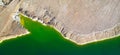 Shore of toxic green lake in abandoned open pit copper mine. Aerial panorama from directly above