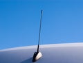 Short black antenna on gray surface against sky