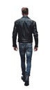 back view of walking young man in leather jacket and jeans, isolated on white.