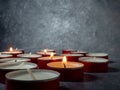 Short candles are burning against a dark background. Lots of small candles. Extinguished Royalty Free Stock Photo