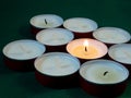 Short candles are burning on a green surface. Lots of small candles. Not all candles are lit Royalty Free Stock Photo