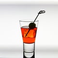 Short drink glass with red liquid, olive, ice cubes Royalty Free Stock Photo