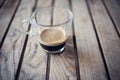 Short espresso coffee served on a transparent glass cup isolated on a striped wooden table Royalty Free Stock Photo