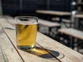 Short glass of blond beer sitting on outdoor table during summer day` Royalty Free Stock Photo