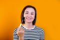 Asian young beautiful woman applying cosmetic powder brush on smooth face isolated over yellow background. Royalty Free Stock Photo