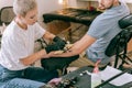 Short-haired attentive tattoo artist taking off paper sketch from skin surface