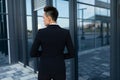 Short-haired business lady in a jacket stands with her back and walks to the front door of a modern office building Royalty Free Stock Photo