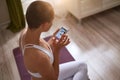 Close-up photo of attractive woman sitting on mat, holding a phone in hands Royalty Free Stock Photo