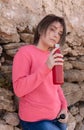 Short-haired Teenage girl in pink hoodie staying near a stone wall with red water bottle Royalty Free Stock Photo