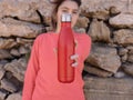 Short-haired Teenage girl in pink hoodie staying near a stone wall with red water bottle Royalty Free Stock Photo