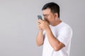 Short or long sighted concept : Man trying to look closer on smarthphone in studio shot on grey