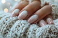 short nails with white and pink nail polish, winter themed, in a knitted sweater, closeup photo, soft light, pastel Royalty Free Stock Photo