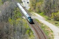 Short passenger train passes through wooded area.