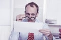 Short sighted at work - balding businessman looking through glasses at document