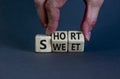 Short and sweet symbol. Businessman turns wooden cubes and changes the word `short` to `sweet` or vice versa. Beautiful grey Royalty Free Stock Photo