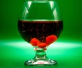 Short whiskey glass with a dark red cocktail with bubbles and cherries in the bottom with a solid green background copy space Royalty Free Stock Photo