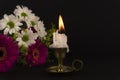 Short candle burning in close-up among flowers Royalty Free Stock Photo