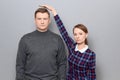 Short woman is standing on tiptoes and showing height of tall man Royalty Free Stock Photo