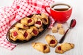 Shortbread cookies with jam in dish on napkin, cup of tea, sugar cubes, teaspoon, cookies on table