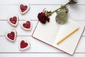 Shortbread heart shaped cookies with empty notebook, pencil and rose flower on white wooden background for Valentines Royalty Free Stock Photo