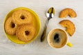 Shortbread rings with sesame in saucer, spoon, broken cookie, cup with coffee on wooden table. Top view Royalty Free Stock Photo