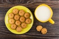 Shortbread in yellow saucer, cup of milk on dark table Royalty Free Stock Photo