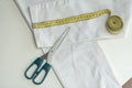 Shortening jeans. White jeans, Measuring tape, scissors on table. Jeans cutting