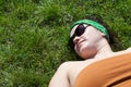 Shot from above of a beautiful young woman in sunglasses black lying on the grass in summer