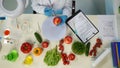 In the shot above, a scientist is sitting. Around her on the table are vegetables and laboratory supplies. Shes holding