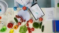 In the shot above, a scientist is sitting in a laboratory. Around her on a table are vegetables, herbs, and lab supplies Royalty Free Stock Photo